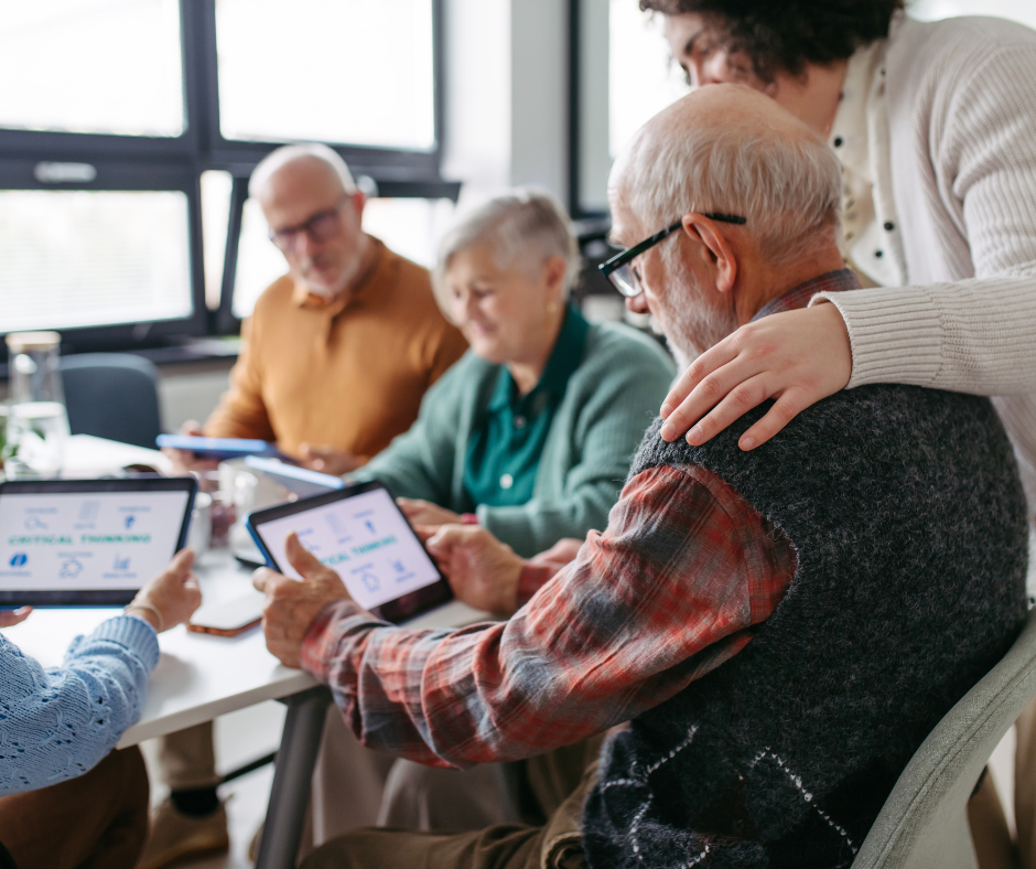 A woman works with several older adults using tablets